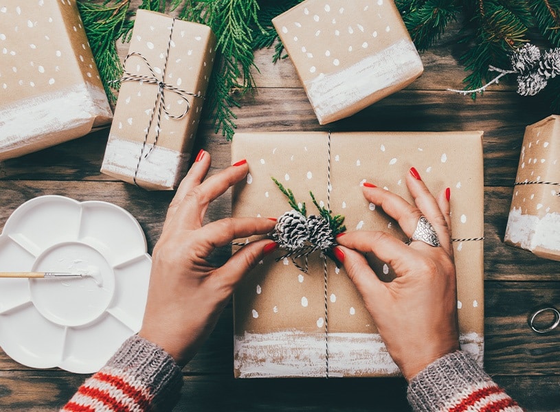Una mujer decora una caja de regalo de Navidad